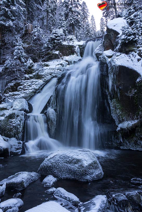 Eine Stufe der vereisten Triberger Wasserfälle im Winter